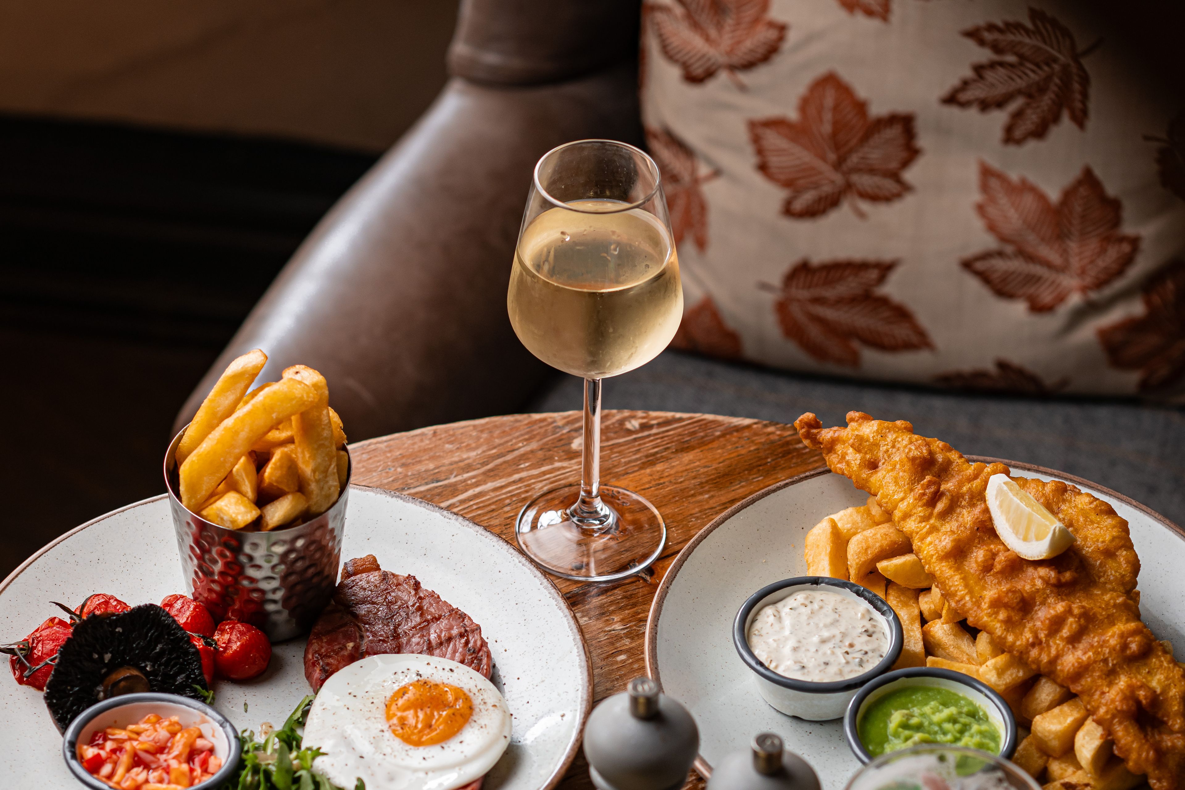 fish and chips dish and gammon steak dish with a glass of wine
